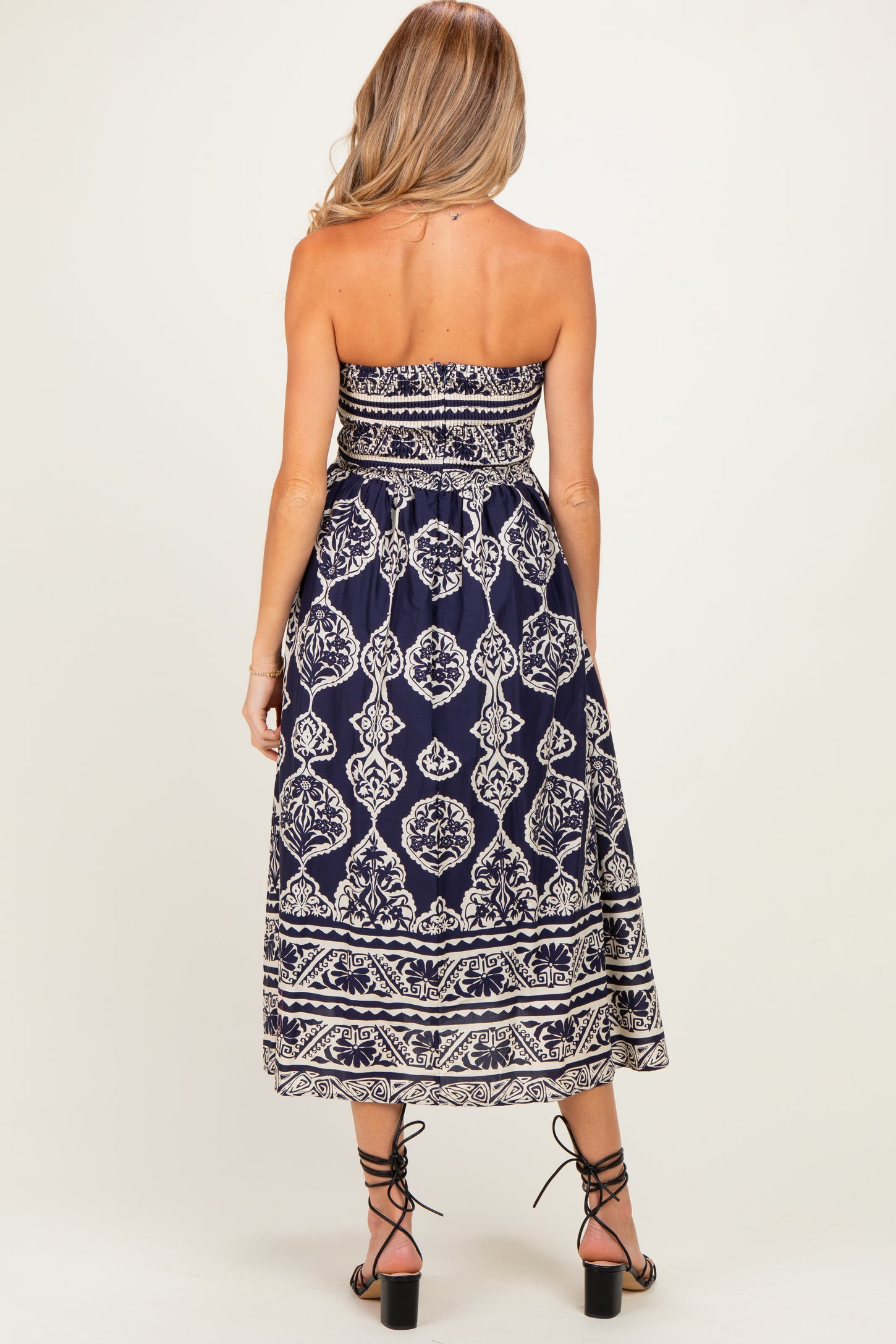 woman wearing a navy blue strapless maternity maxi dress with white floral patterns and a flowy skirt, showing her back