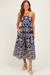 woman wearing a navy blue strapless maxi dress with a floral pattern and pockets