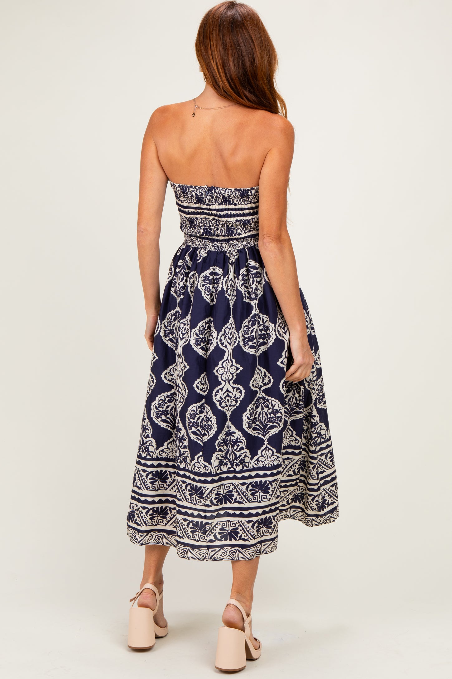 woman wearing a navy blue strapless maxi dress with a white floral pattern and a fitted bodice