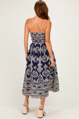 woman wearing a navy blue strapless maxi dress with a white floral pattern and a fitted bodice