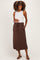woman wearing a white sleeveless maternity top and a brown maxi skirt with a drawstring, showcasing her baby bump