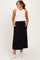 woman wearing a white ribbed tank top and a black maternity maxi dress with pockets and a drawstring waist