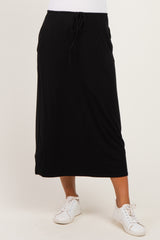 woman wearing a black maternity maxi skirt with a drawstring waist and paired with white sneakers