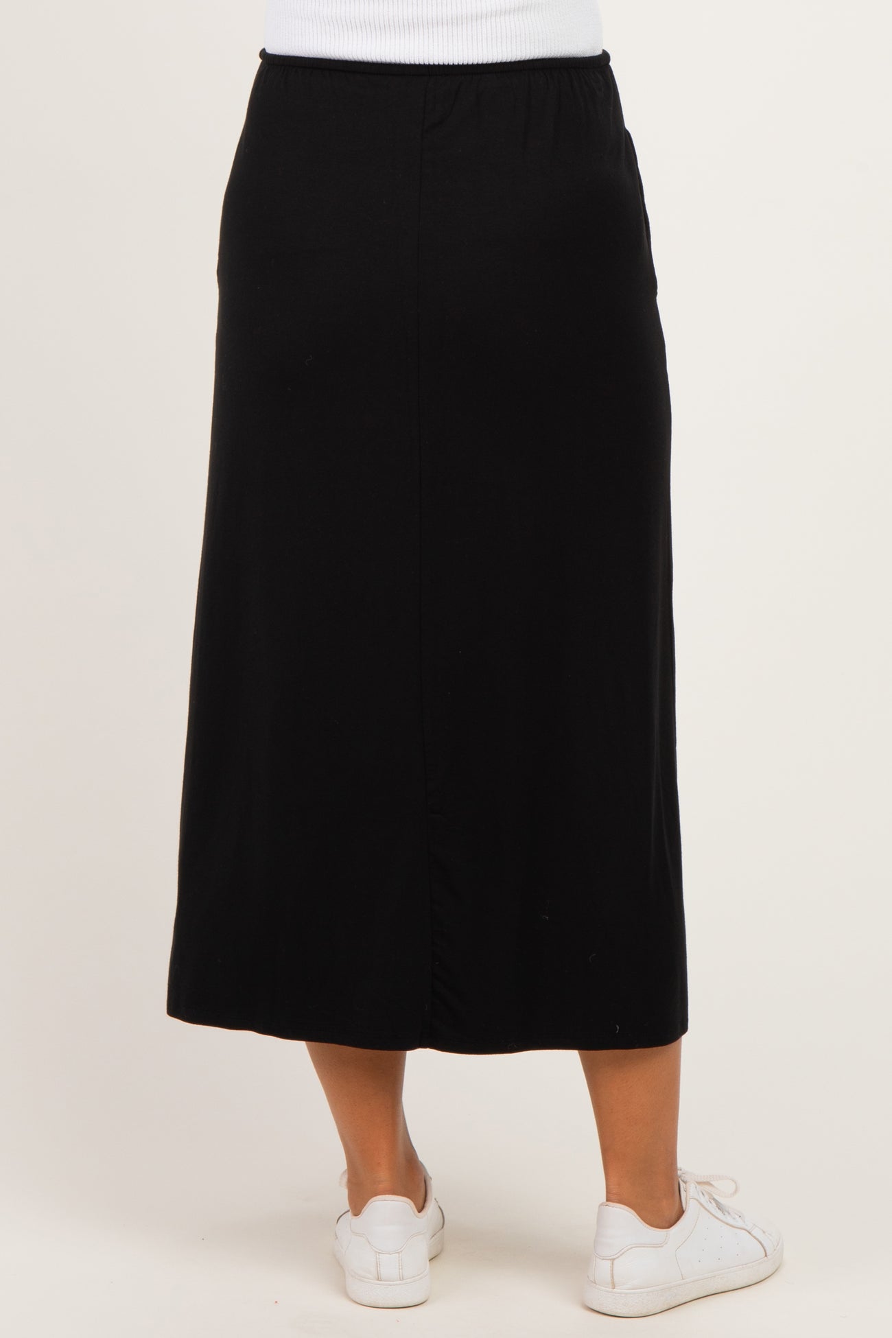 woman wearing a black maternity midi skirt with an elastic waistband and side slit, viewed from the back