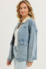 woman wearing a light blue denim jacket with a beige collar and pockets, styled with a white tank top and light jeans