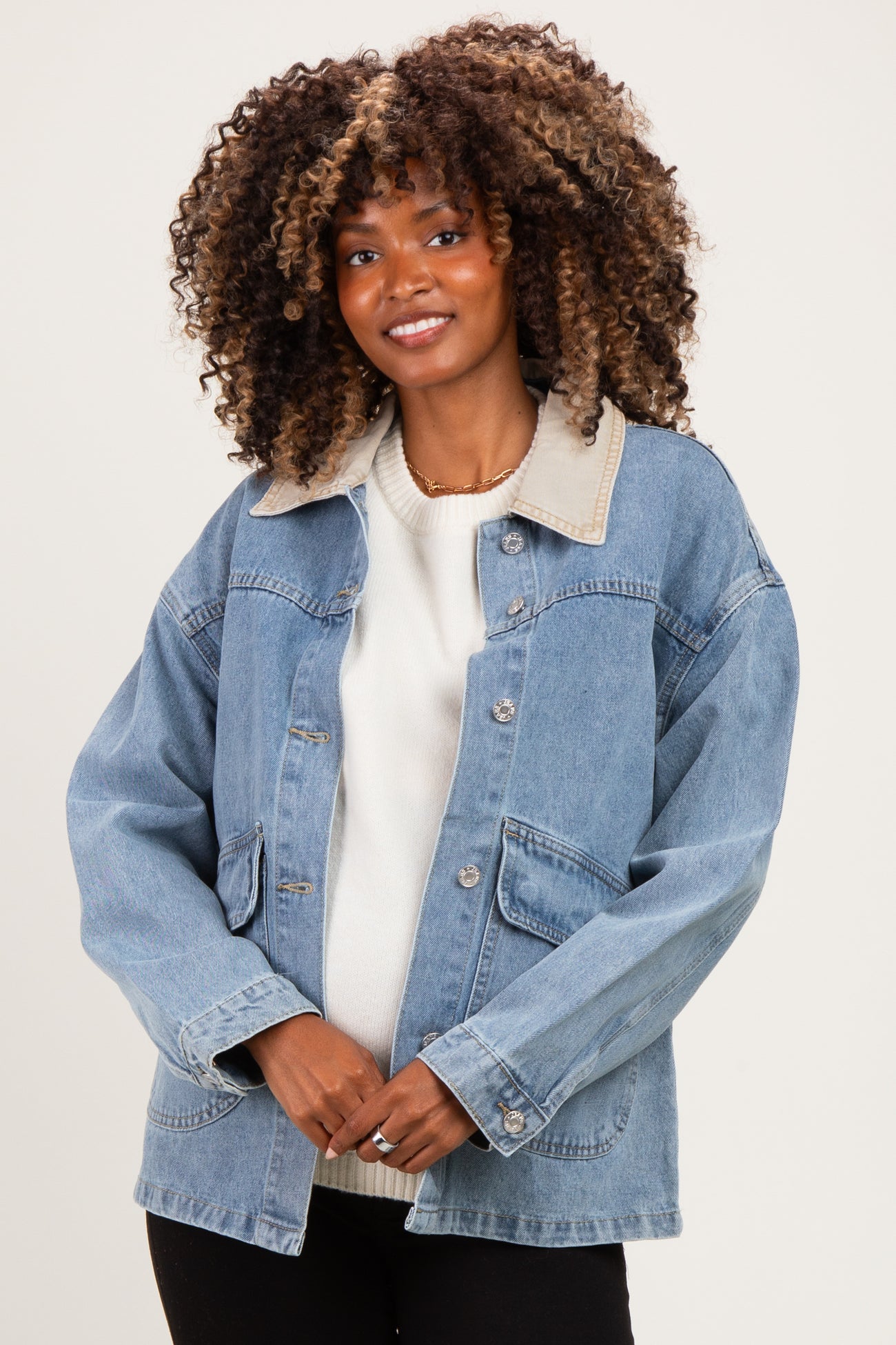 woman wearing a light blue denim maternity jacket with a beige collar and pockets, modeling with a baby bump visible
