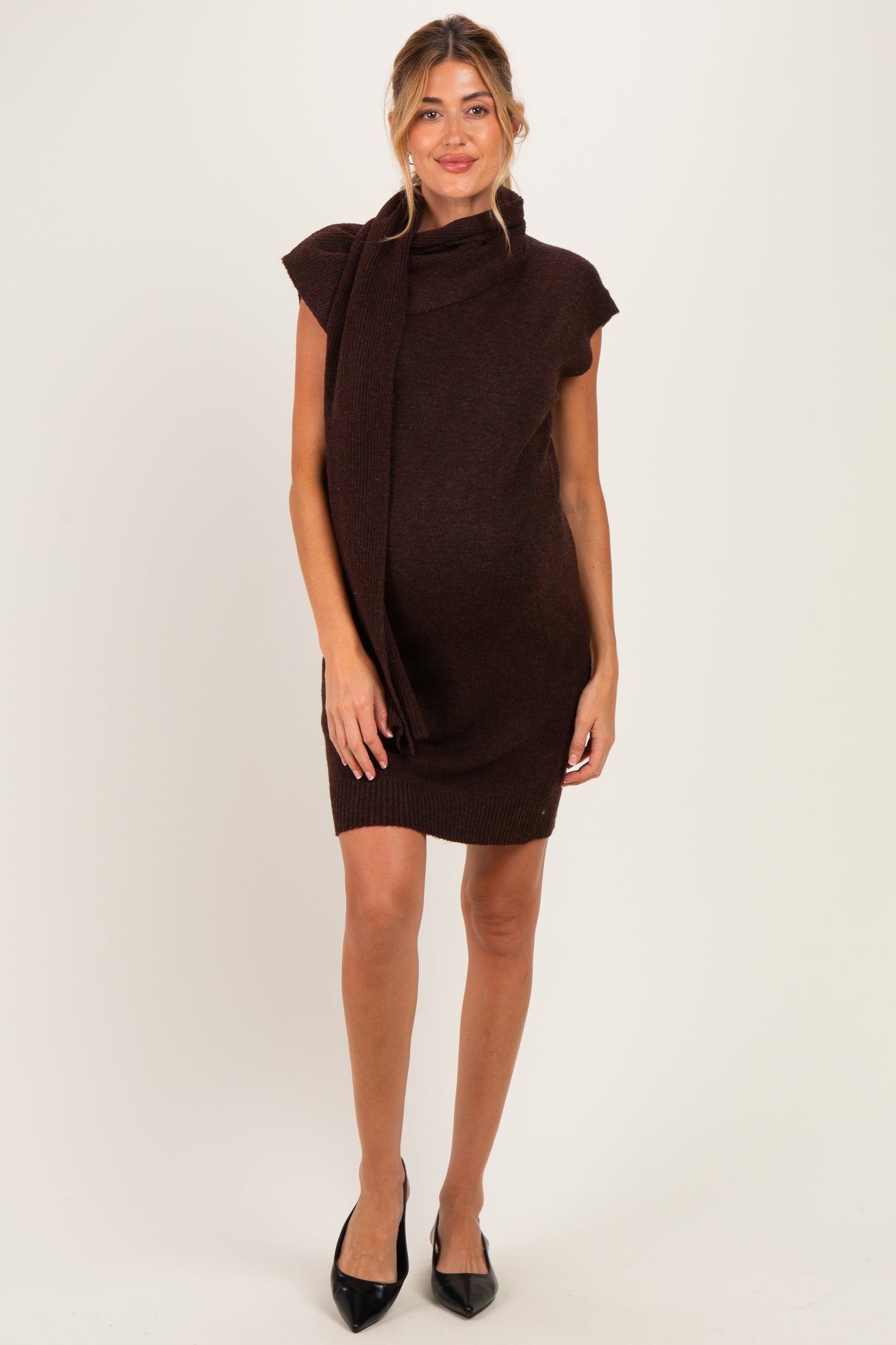 woman wearing a brown short sleeve knitted maternity dress with a stylish scarf detail and visible baby bump