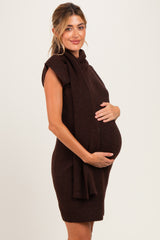 woman wearing a chocolate brown sleeveless maternity sweater dress and holding her baby bump