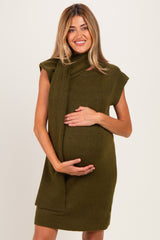 woman wearing an olive green sleeveless maternity dress with a scarf detail and holding her baby bump