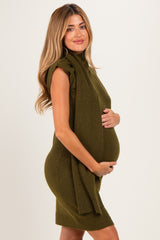 woman wearing an olive green maternity dress with a turtleneck and side tie, holding her baby bump