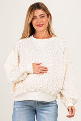 woman wearing a cream maternity sweatshirt with floral print and a baby bump visible