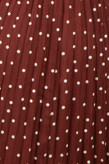 maternity wear in a rust-colored dress with white polka dots and pleated details