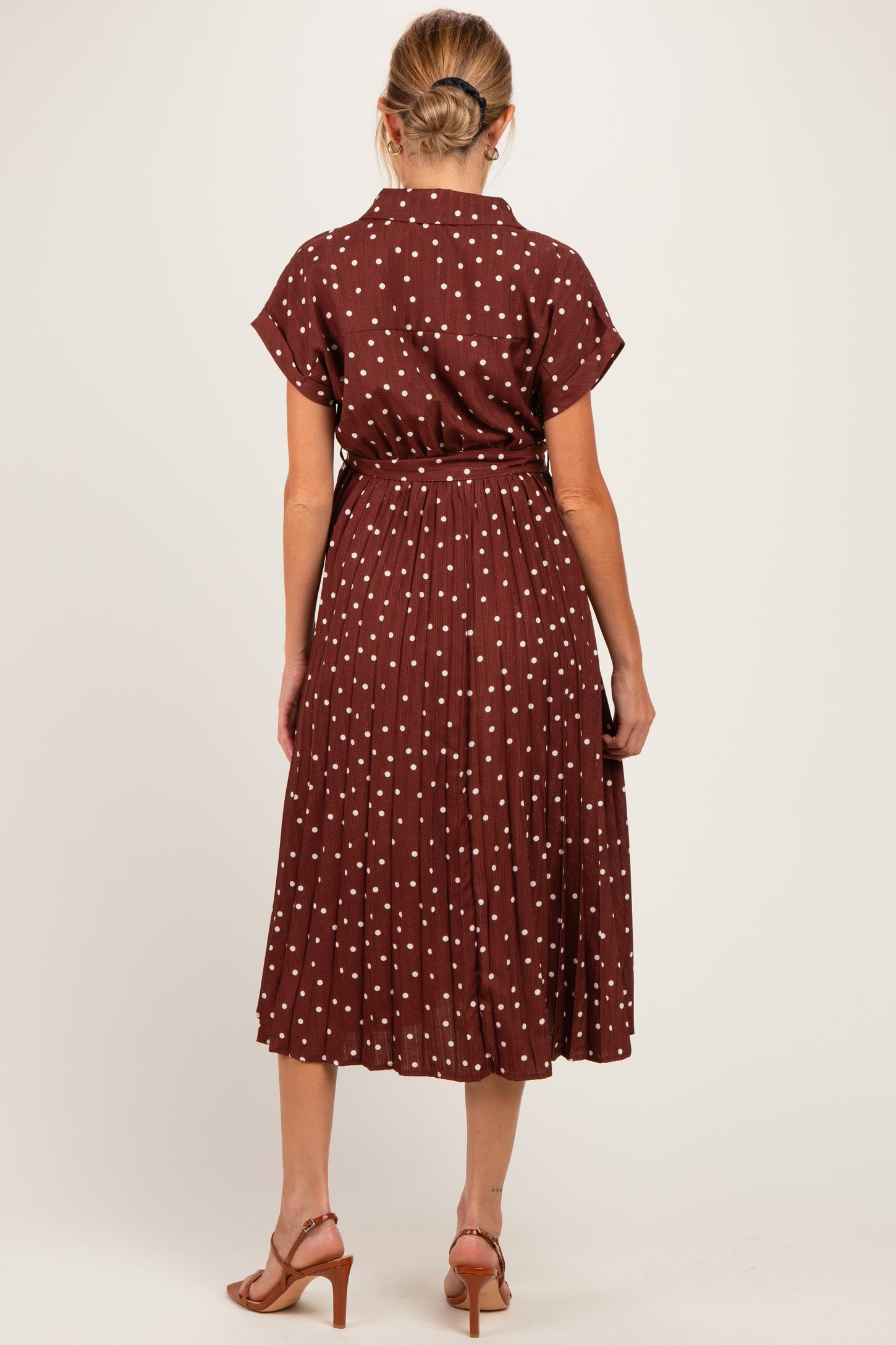 woman wearing a brown maternity dress with white polka dots and a belted waist, shown from the back