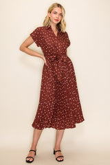 woman wearing a burgundy short sleeve collared dress with white polka dots and a tie belt, model standing in a relaxed pose