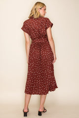 woman wearing a maroon polka dot midi dress with short sleeves and a cinched waist, shown from the back