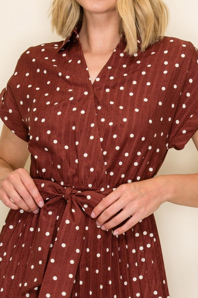 woman wearing a rust-colored polka dot dress with a tie waist and short sleeves