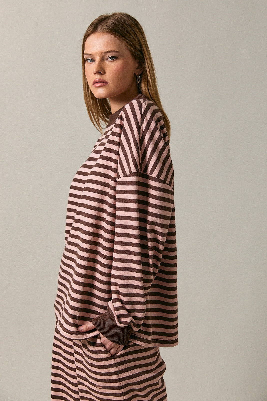 woman wearing a brown and pink striped long sleeve top with relaxed fit and wide sleeves