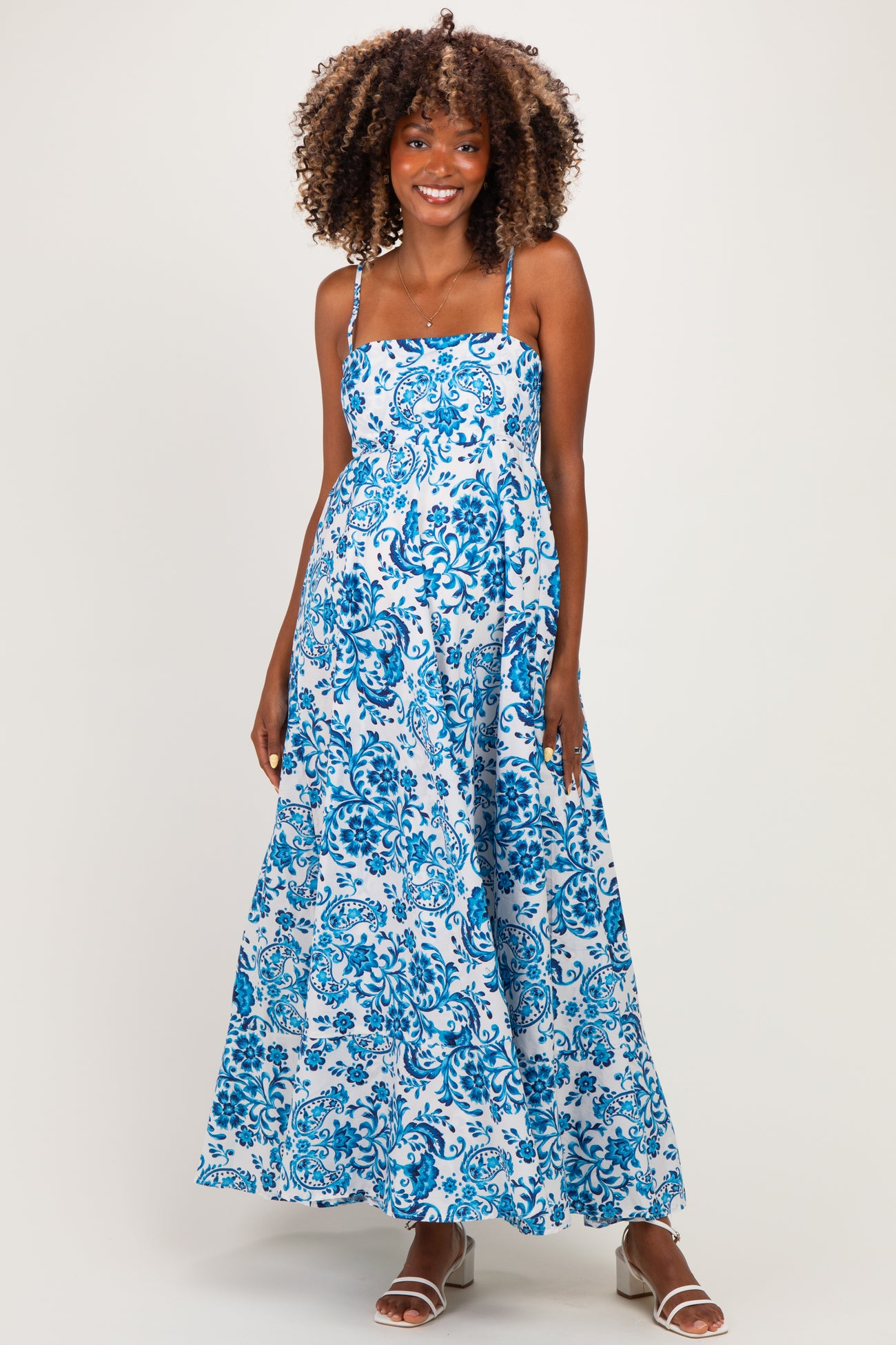 woman wearing a blue and white floral maternity maxi dress with thin straps and a flowy silhouette