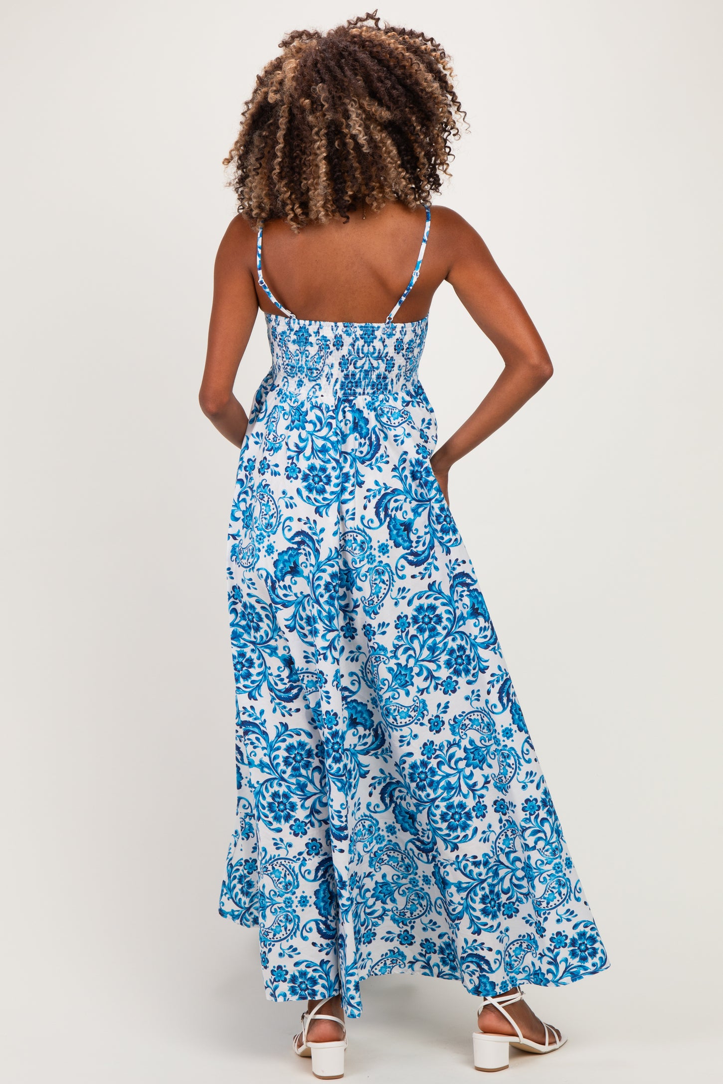 woman wearing a blue and white floral maternity maxi dress with adjustable straps and smocked back design