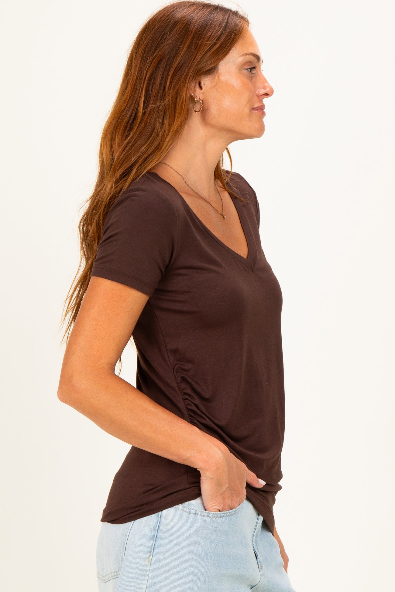 woman wearing a chocolate brown v-neck short sleeve top with side ruching and light blue jeans