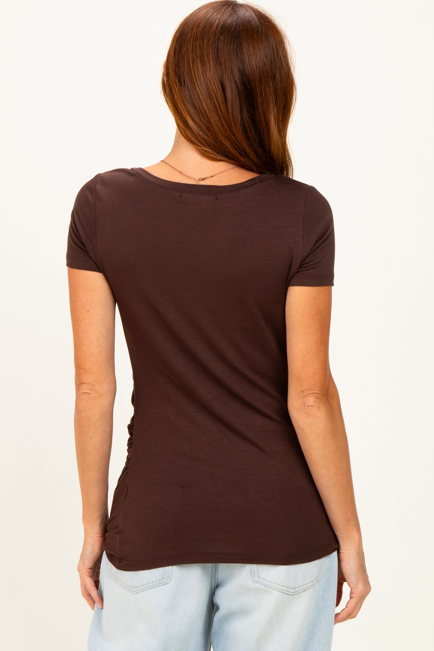 woman wearing a fitted brown short sleeve top with ruching details at the sides