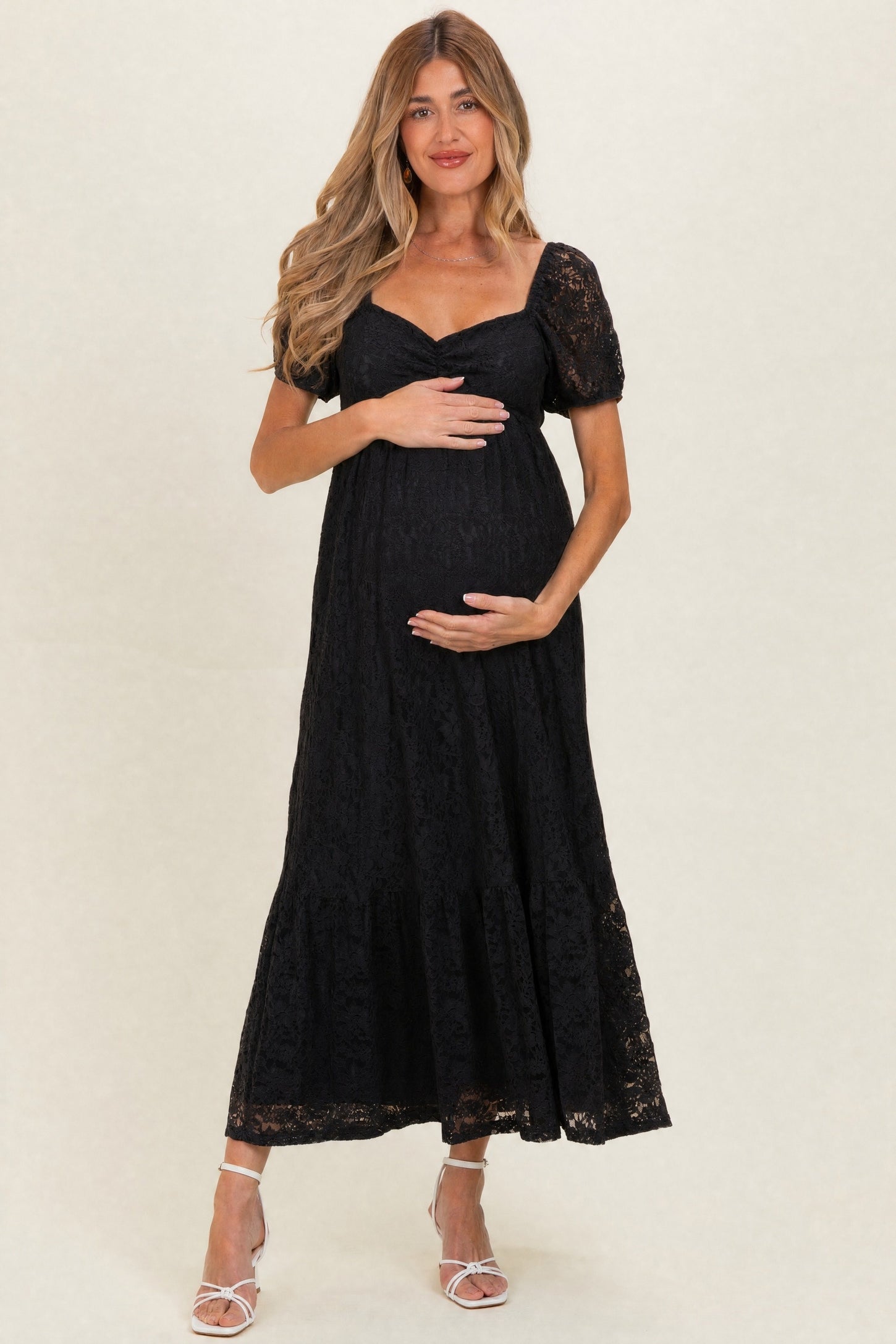 woman wearing a black lace maternity dress with short puff sleeves and a baby bump