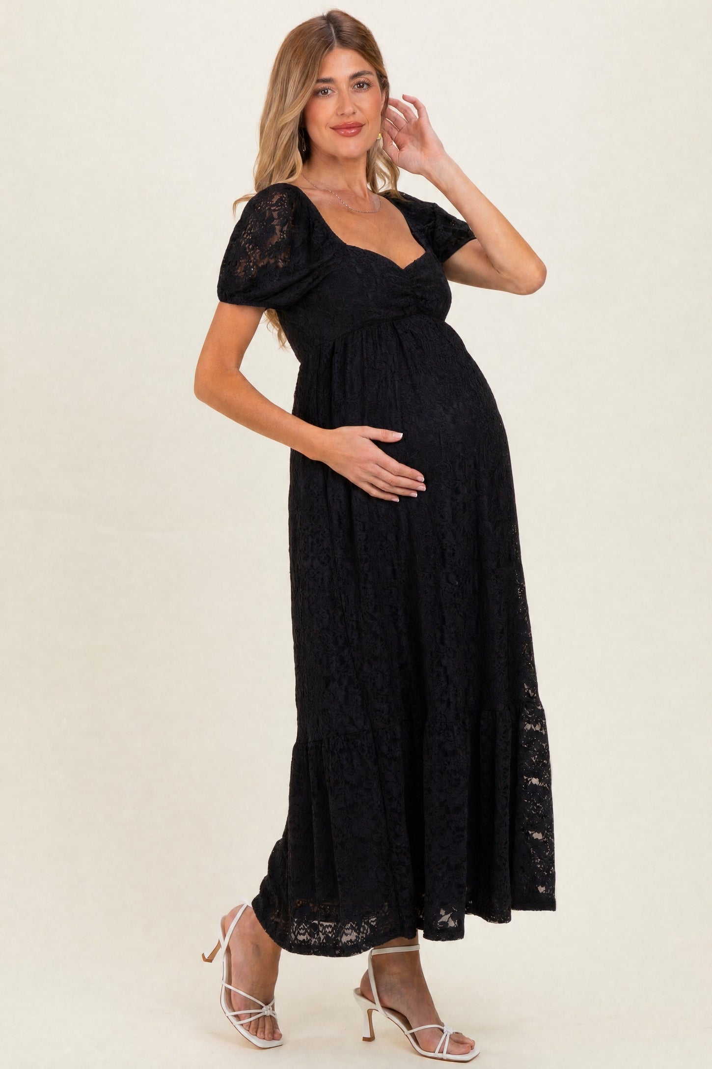 woman wearing a black lace maternity maxi dress and holding her baby bump