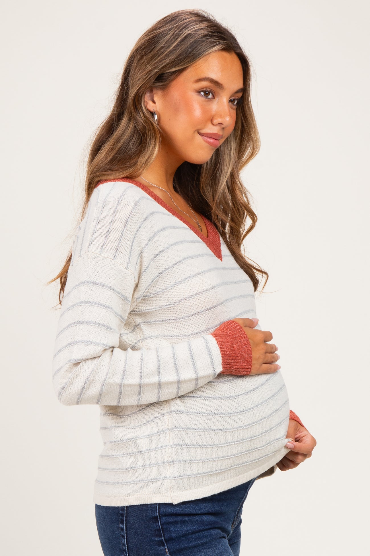woman wearing a striped maternity sweater with a v-neck and holding her baby bump