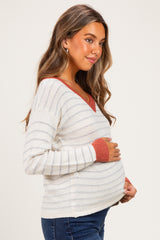 woman wearing a striped maternity sweater with a v-neck and holding her baby bump