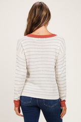 woman wearing a cream and striped maternity sweater with red accents, showing a relaxed fit from the back