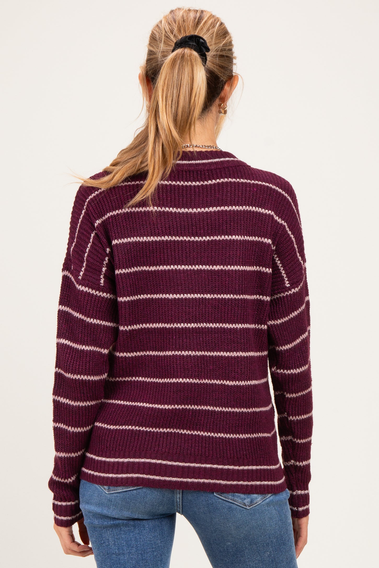 woman wearing a striped maroon maternity sweater with long sleeves and a relaxed fit, seen from the back