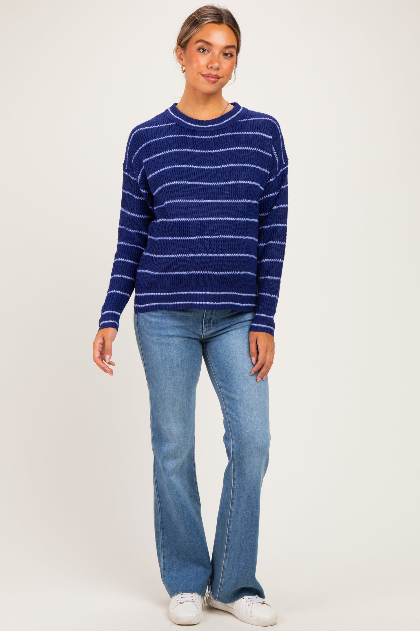 woman wearing a navy blue striped maternity sweater with relaxed fit and light blue flared jeans