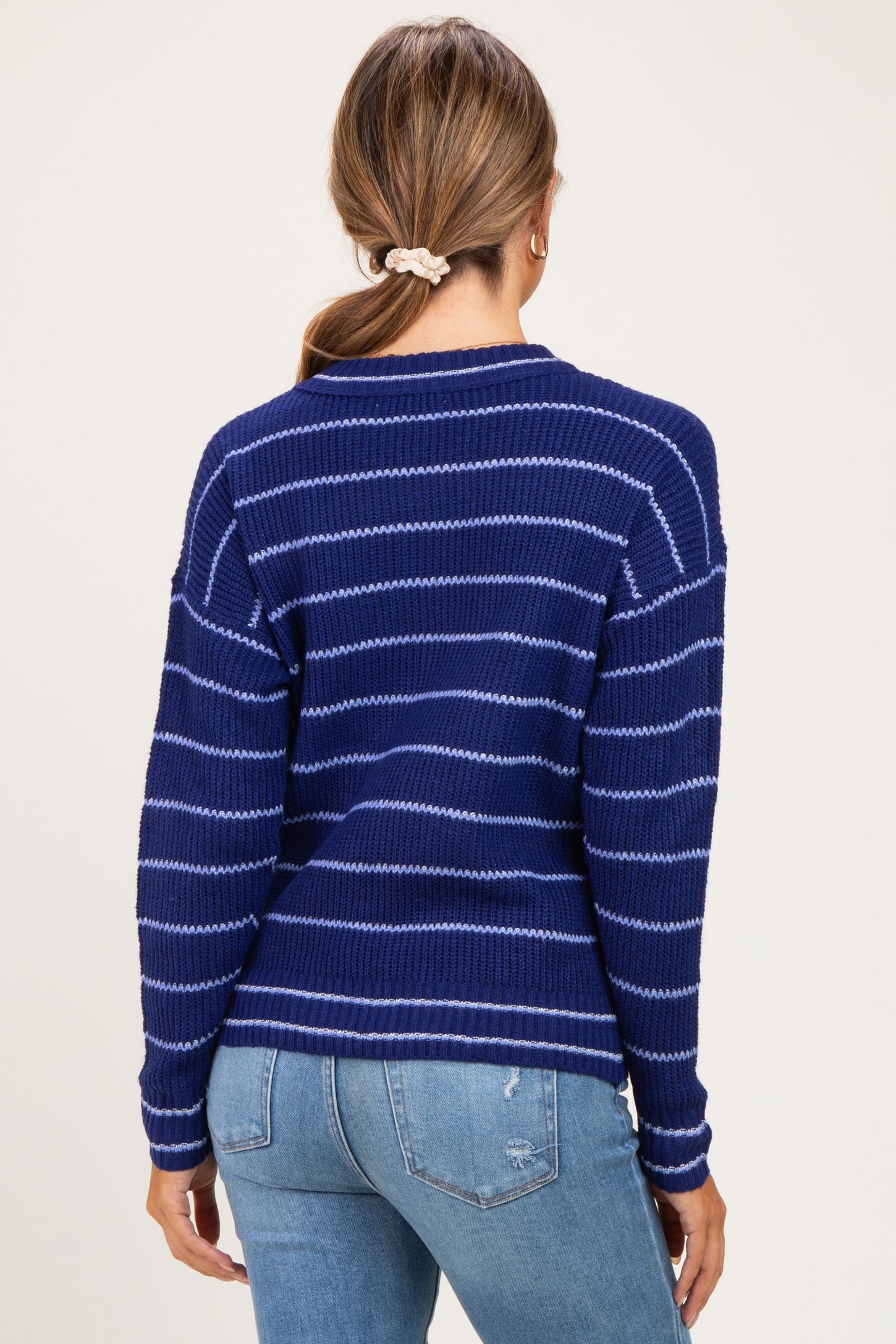 woman wearing a navy blue striped maternity sweater with a relaxed fit and ribbed details, seen from the back