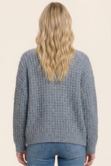 back view of a woman wearing a cozy grey textured sweater with a relaxed fit and ribbed detailing