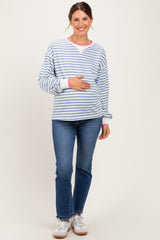 woman wearing a blue and white striped maternity sweatshirt with pink accents and holding her baby bump