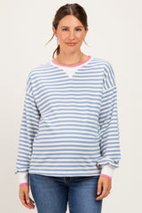 woman wearing a striped light blue and white maternity sweatshirt with pink cuffs and a visible baby bump