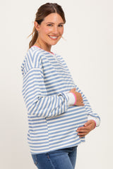 woman wearing a blue and white striped maternity top with pink trim, holding her baby bump