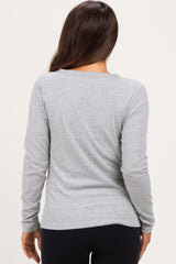 woman wearing a light grey long sleeve maternity top, seen from the back, paired with black leggings