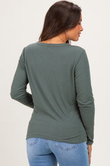 woman wearing a dark green long sleeve maternity top seen from the back paired with light blue jeans
