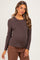 woman wearing a dark brown long sleeve maternity top and displaying her baby bump