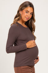 woman wearing a brown long sleeve maternity top and gently holding her baby bump