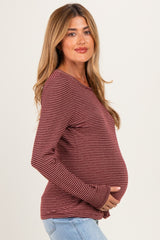 woman wearing a burgundy and white striped maternity long sleeve top and holding her baby bump