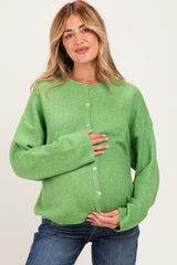 woman wearing a green maternity cardigan and holding her baby bump