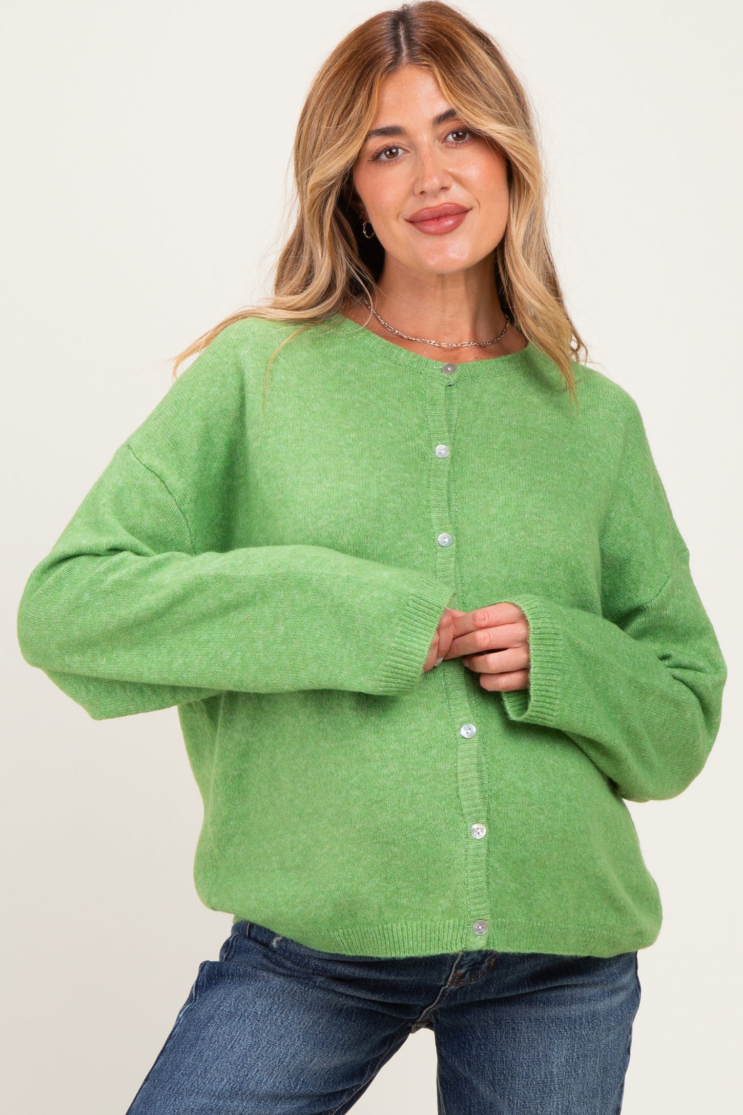 woman wearing a green oversized cardigan with buttons, styled for maternity wear and comfortable fit