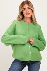 woman wearing a green oversized cardigan with buttons, styled for maternity wear and comfortable fit