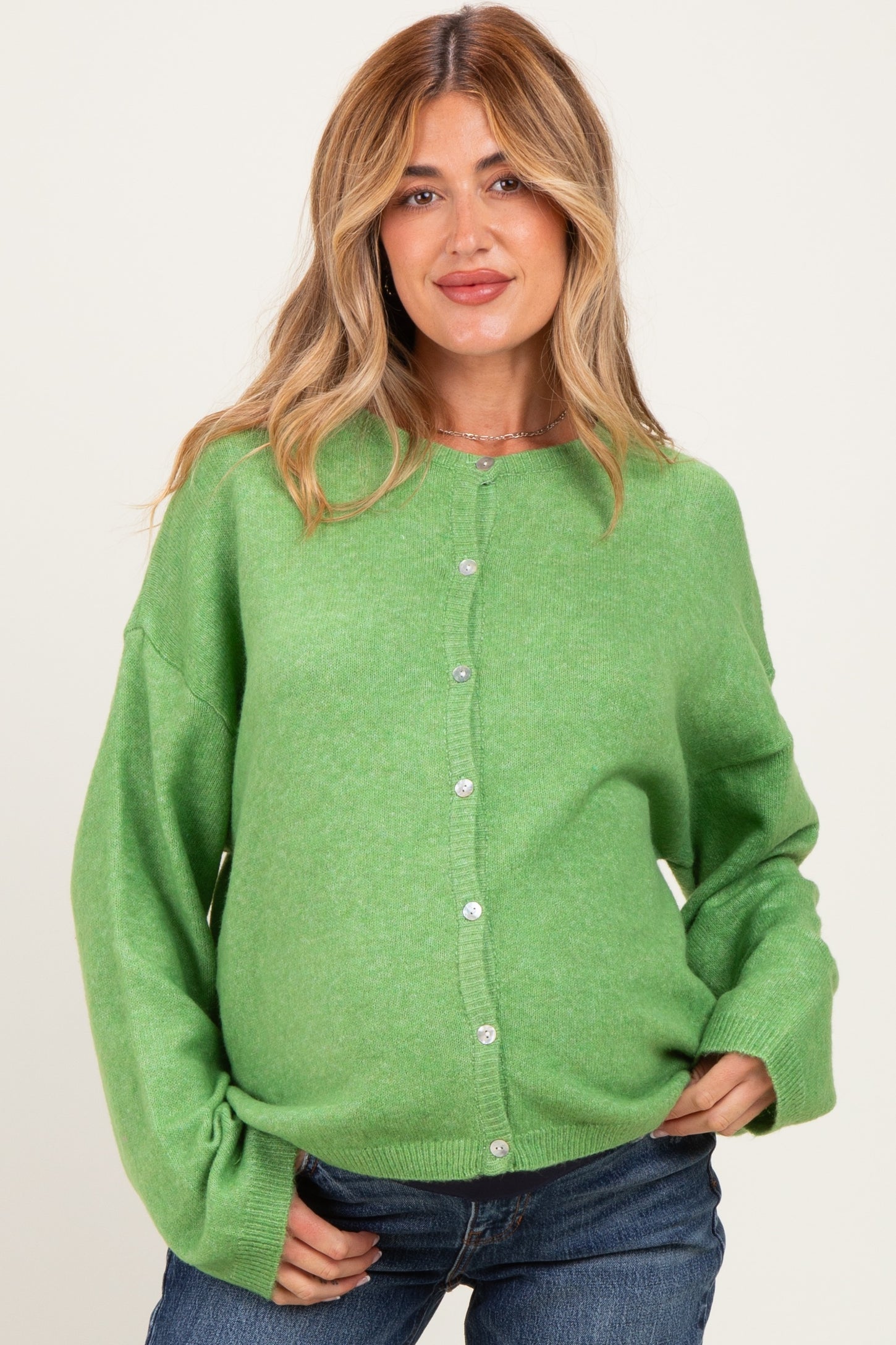 woman wearing a green maternity cardigan with buttons and a visible baby bump