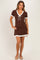 woman wearing a brown short sleeve maternity dress with white trim and a tied neckline, showing off her baby bump