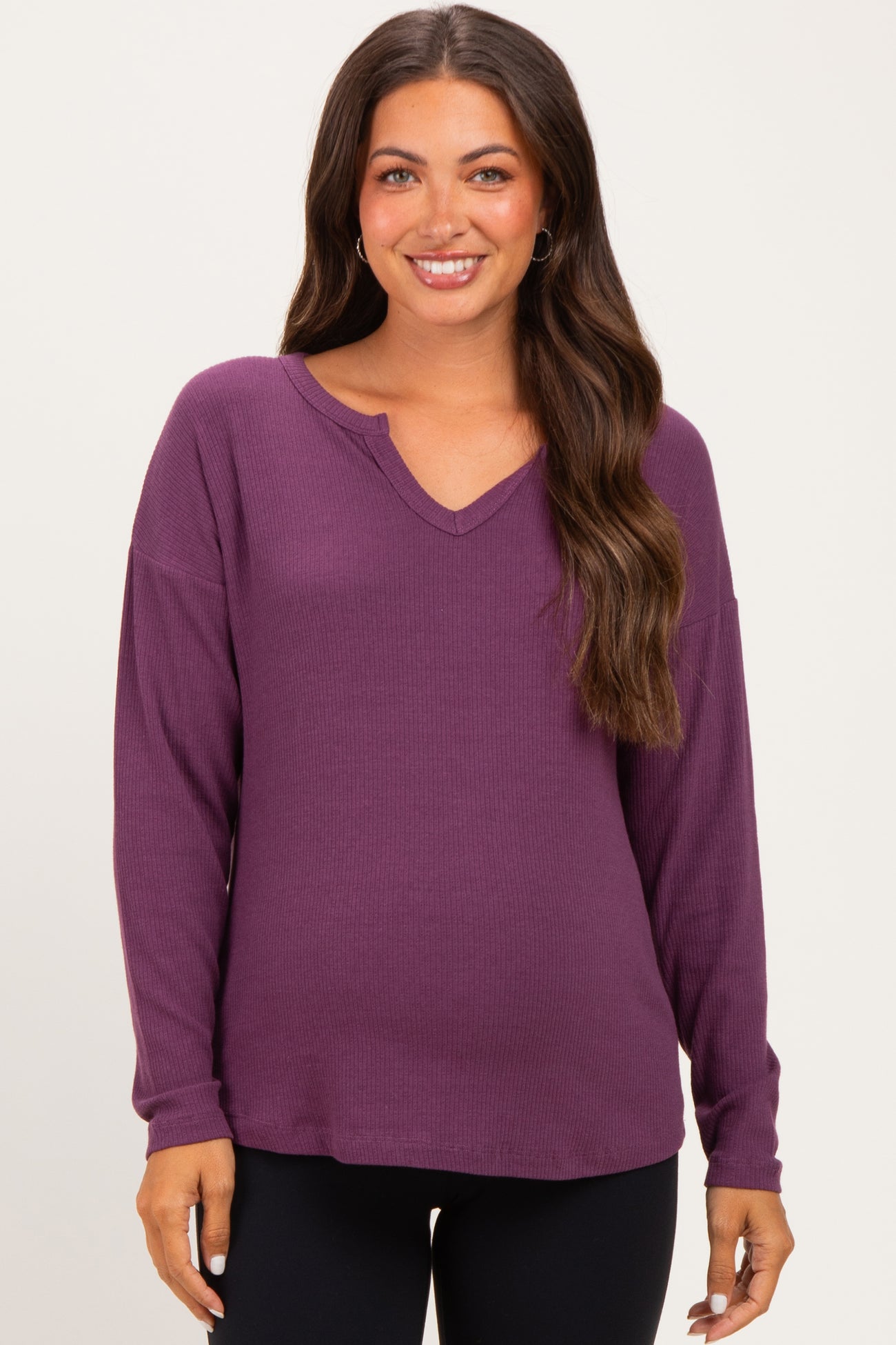 woman wearing a purple long sleeve maternity top with a v-neck and relaxed fit, showing her baby bump