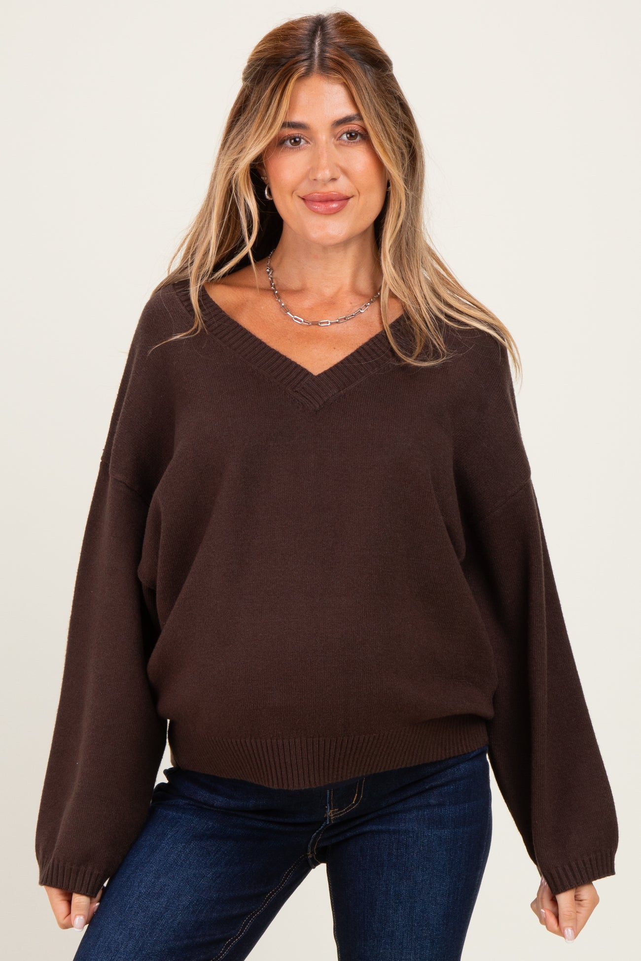 woman wearing a dark brown v-neck maternity sweater with oversized sleeves and a relaxed fit