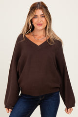 woman wearing a dark brown v-neck maternity sweater with oversized sleeves and a relaxed fit